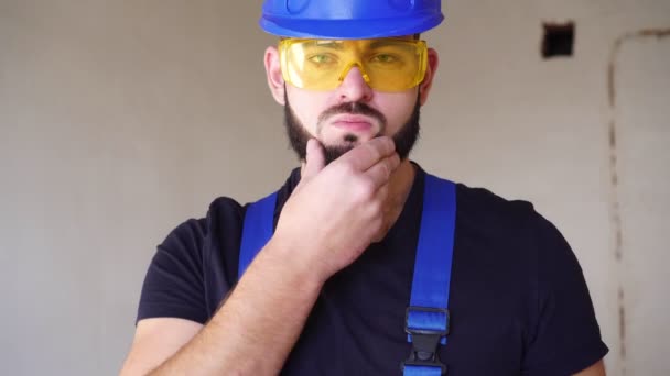Portrait of a young sexy builder in work uniform. Worker at a construction site - Video