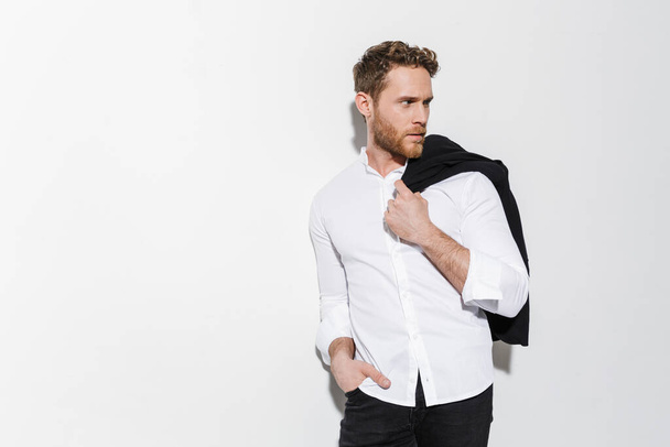 Image of serious man in shirt holding black jacket and looking aside isolated over white background - Photo, Image