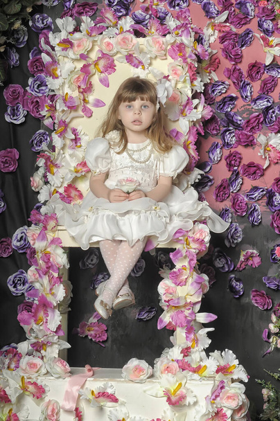 little girl in a white dress on a chair with flowers - Photo, Image