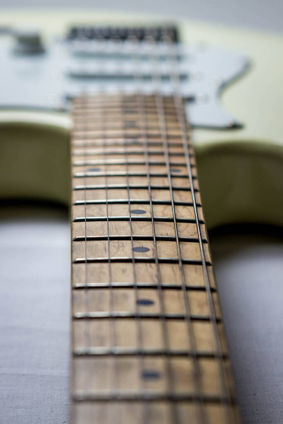 Guitarra elétrica branca sobre fundo branco. Na foto é o pescoço da guitarra
 - Foto, Imagem