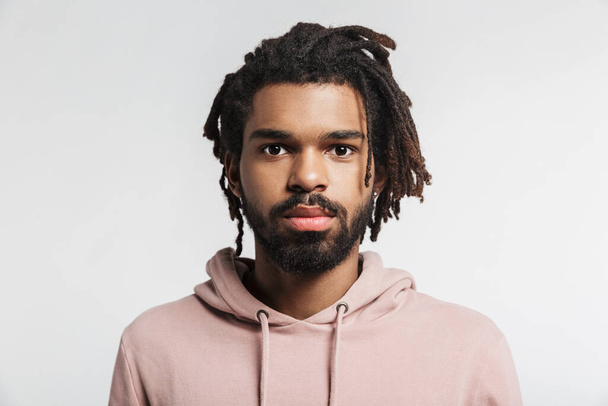 Close up portrait of a young african man wearing hoodie standing isolated over white background, looking at camera - Fotó, kép