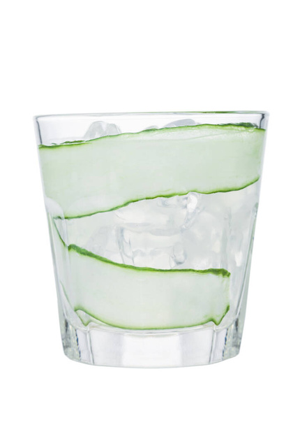 Verse koude komkommer water met ijsblokjes en komkommer plakjes geïsoleerd op witte achtergrond. Gezonde en verfrissende biologische drank. - Foto, afbeelding
