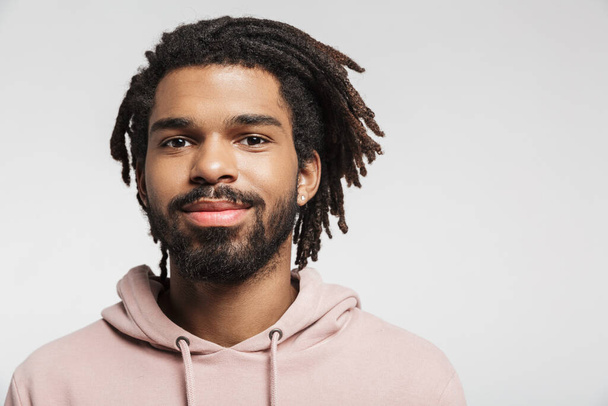 Close up portrait of a smiling young african man wearing hoodie standing isolated over white background, looking at camera - Φωτογραφία, εικόνα