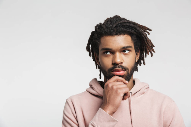 Portrait of a pensive young african man wearing hoodie standing isolated over white background, looking away - Φωτογραφία, εικόνα