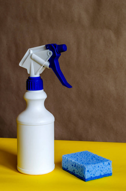 Valkoinen muovipullo spray ja sienellä on kaksivärinen tausta. Valkoinen pullo, jossa on sininen korkki ja laukaisin. Tarvikkeet puhdistukseen ja pesuun. Sivunäkymä lähikuva
. - Valokuva, kuva