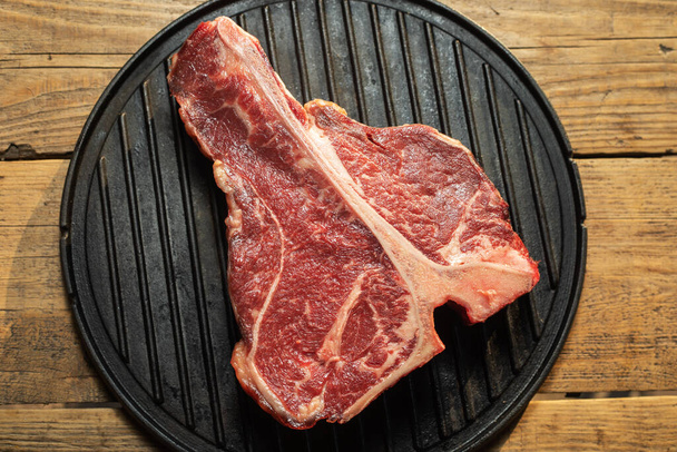 Dikke rauwe T-Bone steak met kruiden en rozemarijn - Foto, afbeelding