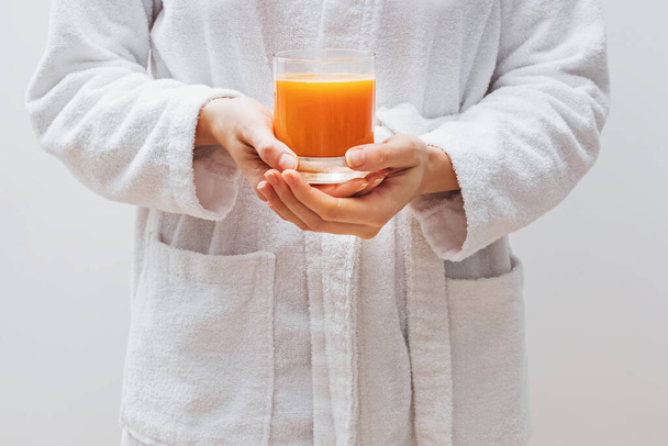 Close-up shot of womans hands holding a glass of fresh citrus juice - Fotoğraf, Görsel