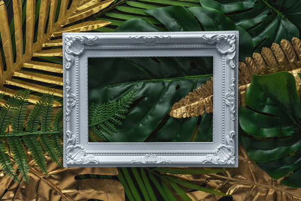 Diseño creativo con hojas de palma tropical doradas y verdes con marco blanco sobre fondo negro. Patrón abstracto de verano mínimo
. - Foto, Imagen