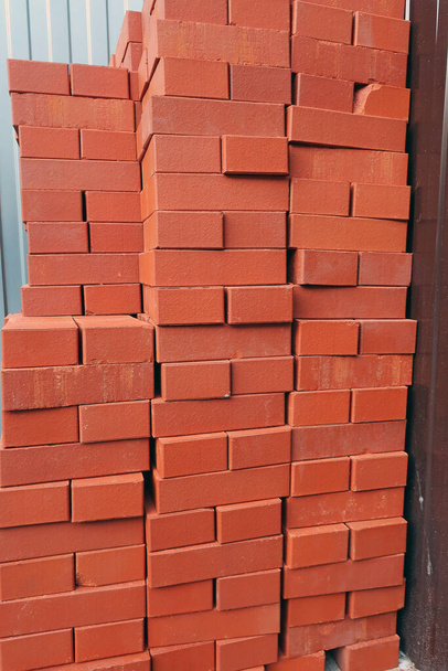στοιβαγμένα πορτοκαλί τούβλα σε εργοτάξιο για τοίχο από τούβλα - Φωτογραφία, εικόνα