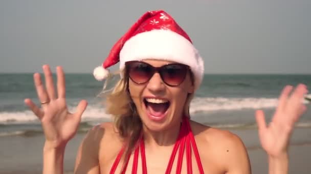 Різдво, щаслива жінка в капелюсі Санта Клауса на пляжі емоційно кричить
 - Кадри, відео