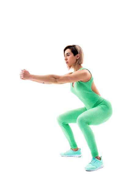 Studio shot of an athletic woman doing squats isolated over white background - Foto, imagen