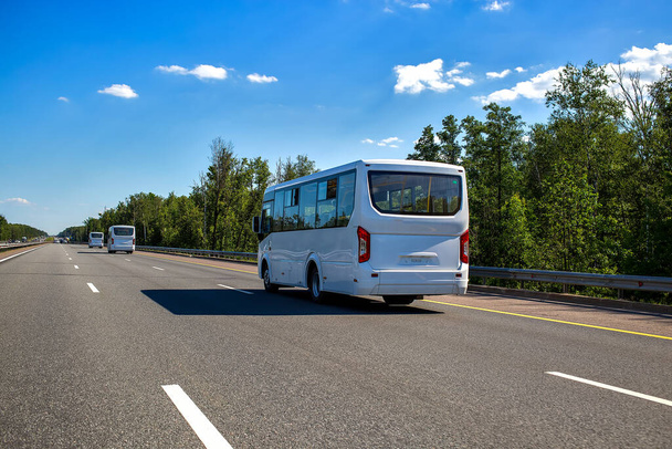 три новых белых микроавтобуса едут в конвое вдоль шоссе в солнечный день летом. крупным планом, вид сзади
 - Фото, изображение