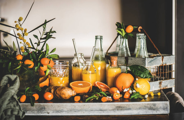 Immune boosting vitamin health defending drink. Turmeric, ginger and citrus juice shots in bottles and fresh ingredients over grey concrete kitchen counter. Pure vegan Immunity system booster - Foto, Bild