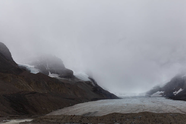 アサバスカ氷河は、カナダのアルバータ州の山からの霧のスライドで覆われています - 写真・画像