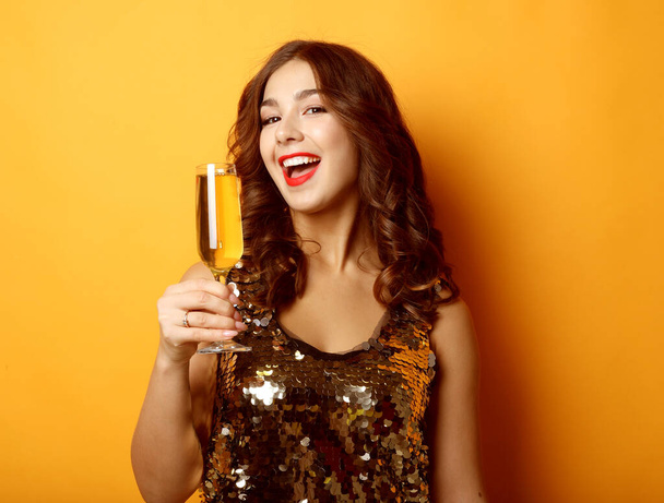 woman in evening dress holding glass of champagne over yellow background - Photo, Image