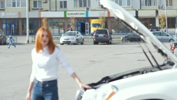 Young stressed woman driver near broken car with popped hood having a prbreakdown problem with her vehicle waiting for assistance. - Video, Çekim