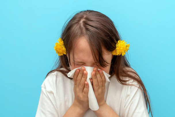 Close-up portrait of a teenage girl with a white scarf who rolls her eyes and sneezes. The concept of seasonal pollen allergy to flowers. The time of spring and summer - Photo, Image