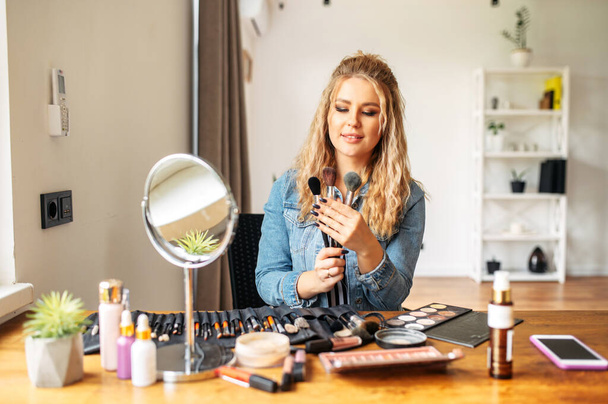 Young woman looks at mirror and doing makeup - Foto, Imagem