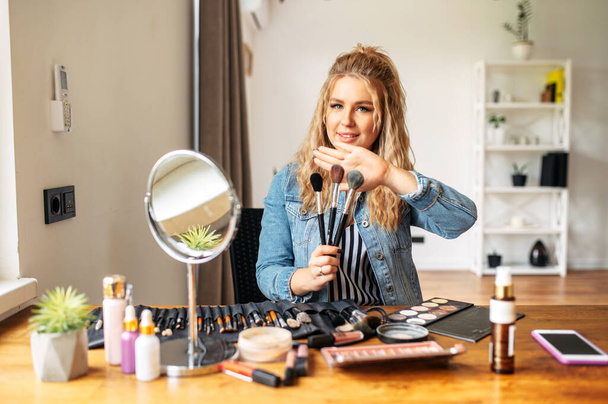 Young woman looks at mirror and doing makeup - Foto, imagen