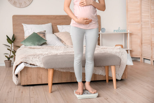 Young pregnant woman measuring her weight at home - Foto, Imagem