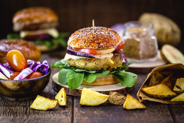 sándwich vegano, hamburguesa vegetal y proteica con fibra, en pan de harina hecho con levadura biológica, papas fritas, cebolla roja, con melón, pimienta y rúcula
. - Foto, imagen