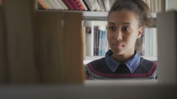 Fiatal afro-amerikai diák az iskolai könyvtárban - Felvétel, videó