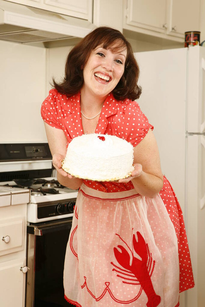 Brunette vrouw met taart in de keuken - Foto, afbeelding