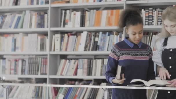 Ευρωπαίες και Αφροαμερικανίδες διαβάζουν βιβλία στη βιβλιοθήκη. - Πλάνα, βίντεο