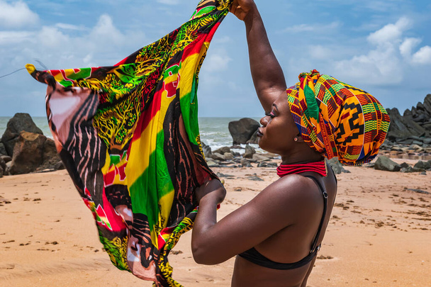 Tančící Ghana žena na krásné pláži Axim, který se nachází v Ghaně západní Africe. Headdress v tradičních barvách z Afriky. - Fotografie, Obrázek