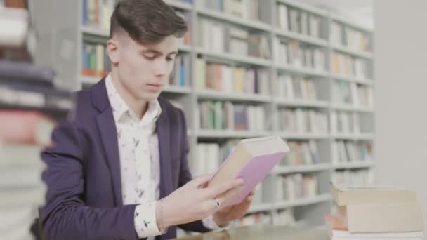 Jonge student in een pak leest een groot Engels leerboek - Video