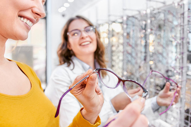 Finding the right frame for prescription glasses in an optical shop - Foto, Bild