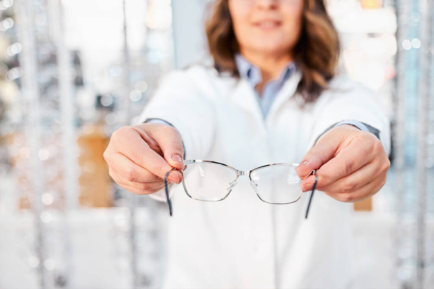Optician sugerindo e mostrando óculos em uma loja óptica, encontrando o quadro certo para óculos de prescrição. Foco em óculos
 - Foto, Imagem