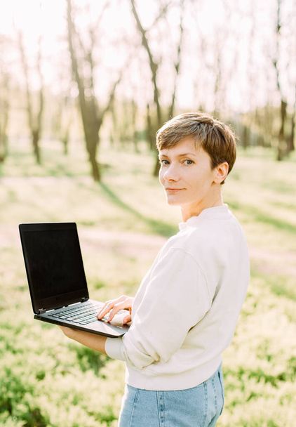 работающая онлайн женщина с ноутбуком в парке связи и технологии
 - Фото, изображение
