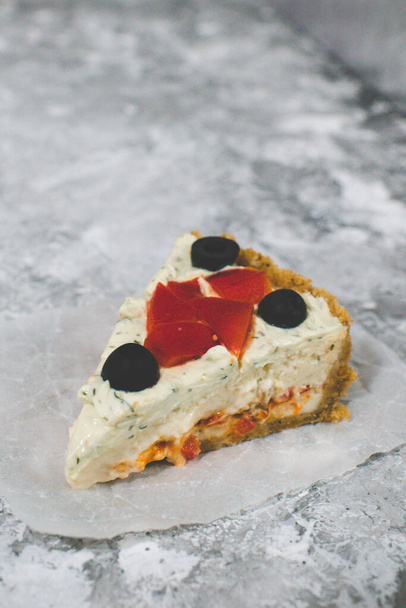 Slice of vegetable cheesecake. Garnished with bell pepper and olives - Photo, Image