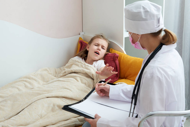 Doctor visiting sick little girl at home and writing prescription, flue concept  - Photo, Image