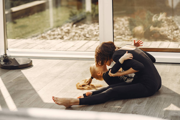 Woman with daughter is engaged in gymnastics - Fotoğraf, Görsel