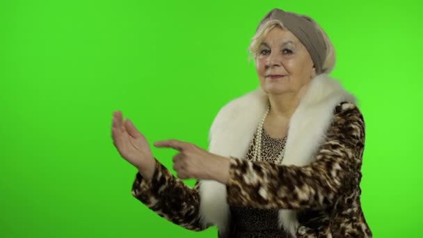 Elderly stylish grandmother. Caucasian woman pointing at something with hand - Footage, Video
