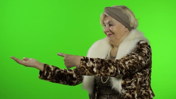 高齢の白人の祖母の女性が手で何かを指しています。クロマキー - 映像、動画