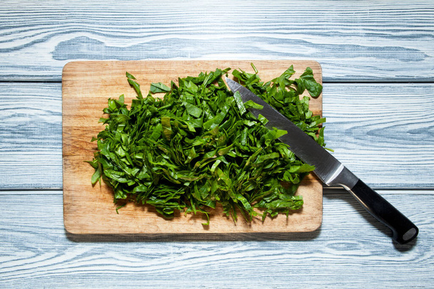 Fresh bright green spinach. Top view. Knife and chopped spinach on a wooden cutting board. - Photo, image
