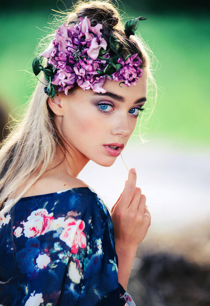 An attractive sensual young girl with a purple flower in her hair. Close-up portrait outdoors, natural female beauty - 写真・画像