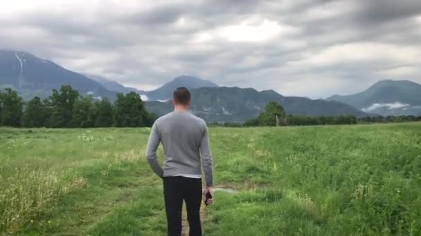 όμορφος άντρας με καθημερινά ρούχα που περπατάει ανάμεσα στα βουνά την καλοκαιρινή μέρα   - Πλάνα, βίντεο