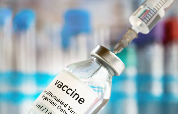Vaccine glass bottle with syringe injected, blurred vials background - Φωτογραφία, εικόνα