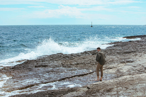 man walking by rocky beach in windy day summer vacation. enjoy sea view. summer time - Photo, image