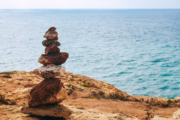 torre de pedra em uma rocha junto ao mar. céu com nuvens, o conceito de harmonia, energia da vida e meditação - Foto, Imagem