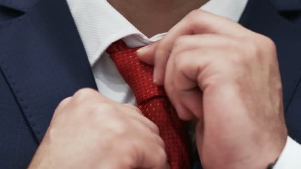 Az üzletember kijavítja a piros nyakkendőt egy fehér ingen. - Felvétel, videó
