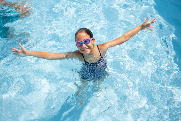 Gelukkig meisje neemt een bad in het zwembad van het hotel tijdens de zomervakantie - Foto, afbeelding