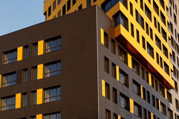 Fragment of a new elite residential building or commercial complex. Part of urban real estate. Yellow-brown modern ventilated facade with windows. Diagonal arrangement - Zdjęcie, obraz