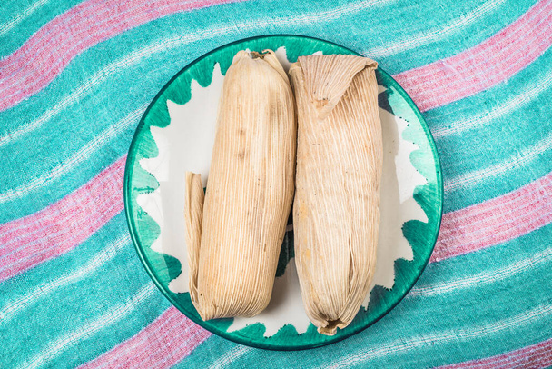 Сладкая Тамале, мексиканское блюдо, приготовленное из кукурузного теста с изюмом и клубничным или ананасовым вкусом, завернутое кукурузным листом
 - Фото, изображение