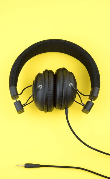 schwarze Kopfhörer auf gelbem Hintergrund, Unterhaltungskonzept - Foto, Bild