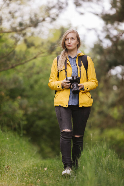 Female photographer walking through green forest - Fotó, kép
